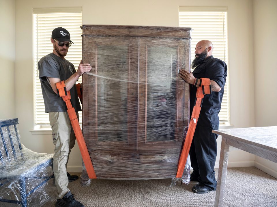 Two installers setting a wrapped armoire in place